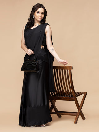 Elegant black pleated saree with satin, strappy blouse, and beads.