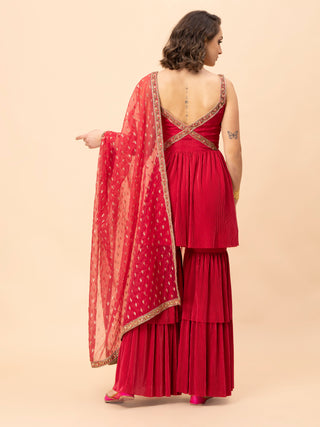 Reddish pink peplum top with zari embroidery and pleated sharara.